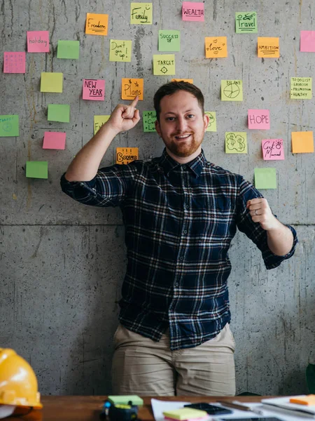 Gelukkig ingenieur man presenteren zijn Sticky Notes grafiek op cement muur — Stockfoto