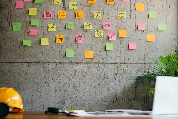 Ingenieur helm, witte laptop op tafel en kleurrijke Sticky Notes — Stockfoto