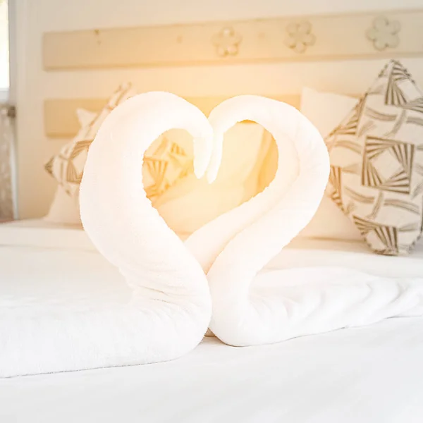 Łabędzie ręczniki na łóżku z sercem znak miłości. — Zdjęcie stockowe
