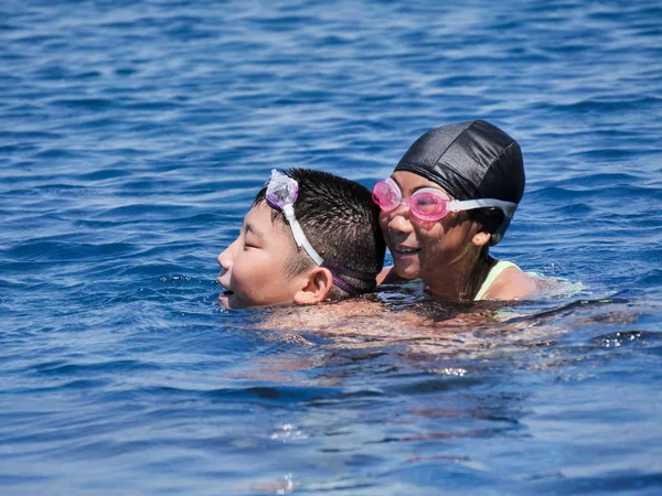 Asiático preadolescente chico piggyback su hermana en piscina en sol día, lif —  Fotos de Stock