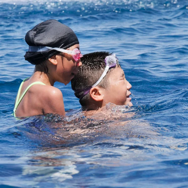 Ásia preteen menino piggyback seu irmã no piscina no ensolarado dia lif — Fotografia de Stock