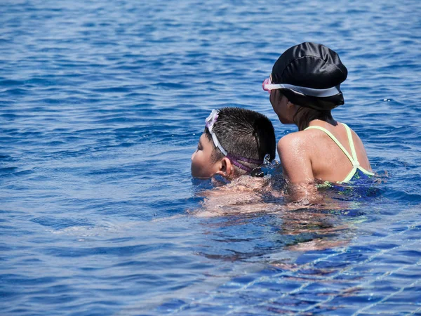 Asiatique preteen garçon piggyback son soeur dans piscine dans sunny jour lif — Photo
