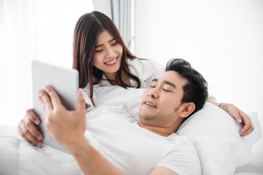 Dizüstü ve tablet birlikte yatakta ho kullanarak mutlu Asya çift