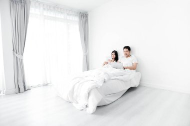 Dizüstü ve tablet birlikte yatakta ho kullanarak mutlu Asya çift