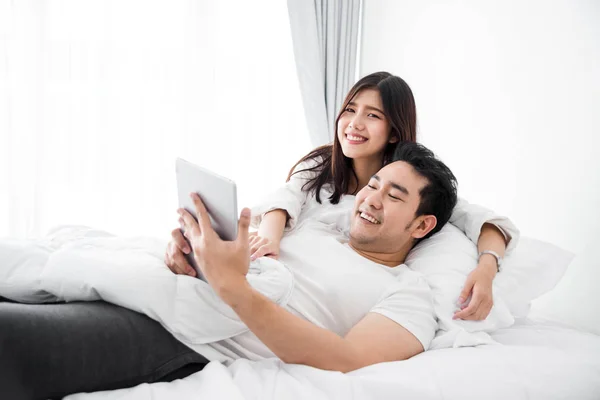 Feliz ásia casal usando laptop e tablet juntos no cama no ho — Fotografia de Stock