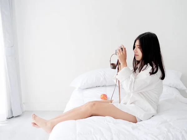 Glücklich asiatische Frau mit vintage Kamera und sitzt auf Bett in die mo — Stockfoto