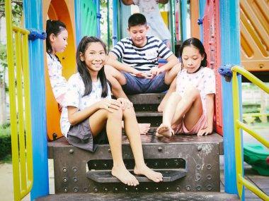 Mutlu Asyalı çocuklar parkta birlikte oyun başında oturan outd