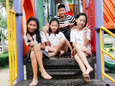 Mutlu Asyalı çocuklar parkta birlikte oyun başında oturan outd