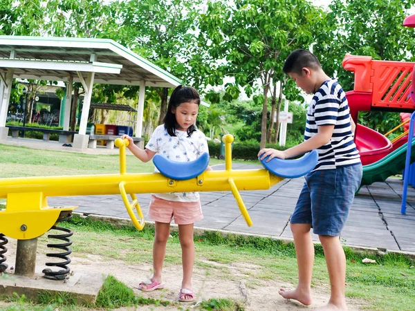 Feliz asiático niños jugando balancín juntos en el parque o — Foto de Stock