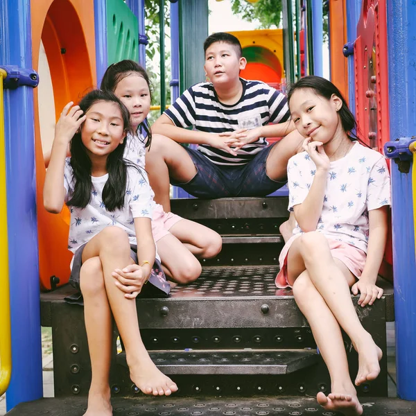 Heureux asiatique les enfants assis à aire de jeux ensemble dans l 'parc outd — Photo