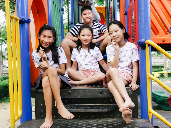 Feliz ásia crianças sentado no playground juntos no o parque outd — Fotografia de Stock