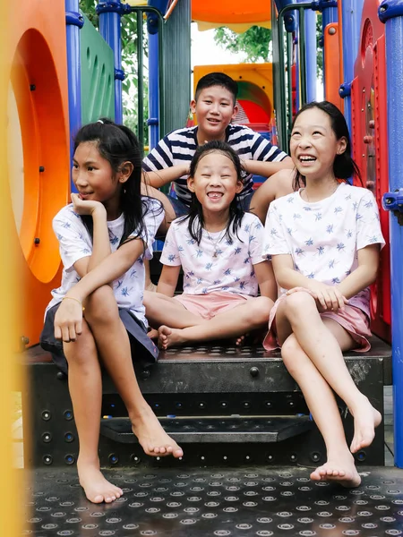 Feliz asiático niños sentado en playground juntos en el parque outd — Foto de Stock