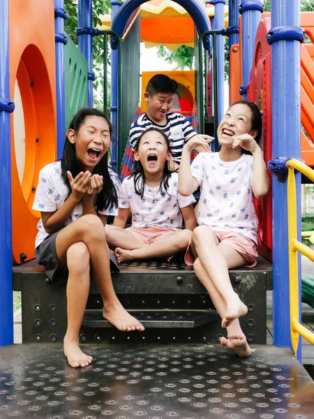 Happy asiatiska barnen sitter på lekplats tillsammans i parken utem — Stockfoto