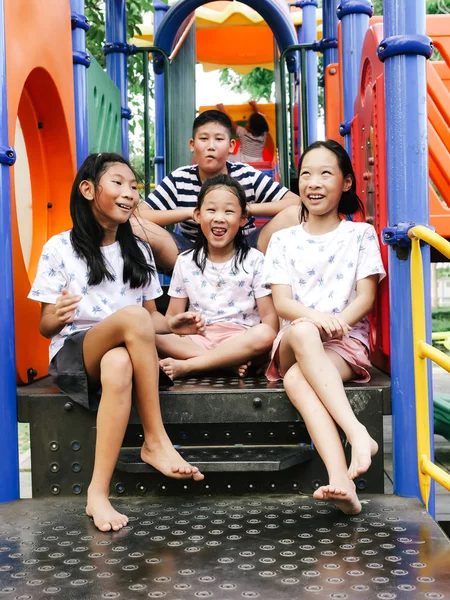 Happy asiatiska barnen sitter på lekplats tillsammans i parken utem — Stockfoto