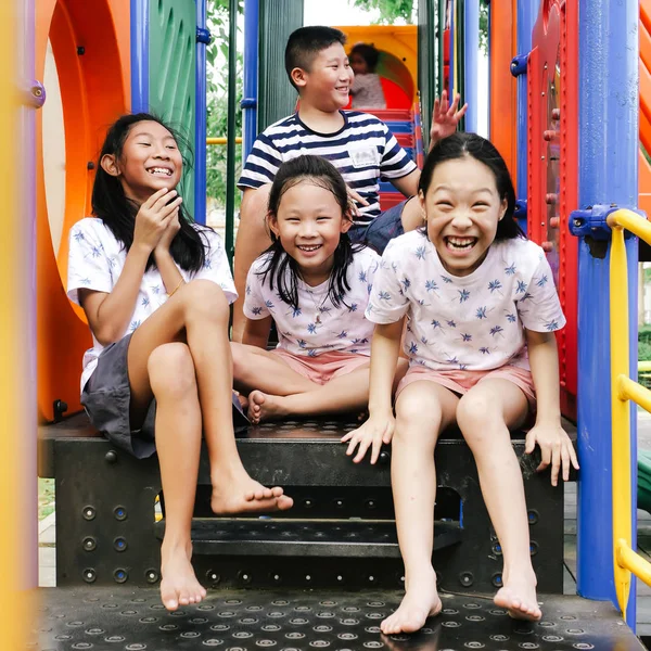 Feliz asiático niños sentado en playground juntos en el parque outd — Foto de Stock