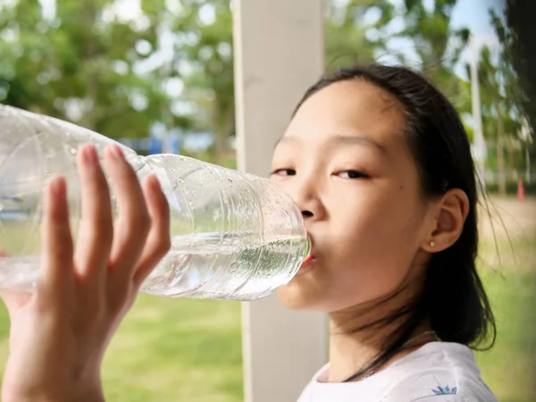 Aziatisch meisje drinken een fles water buiten. — Stockfoto