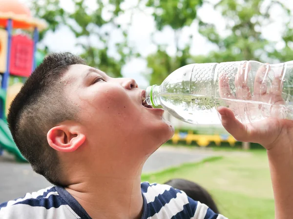 Close up Aziatische jongen is het drinken van water uit plastic fles op de — Stockfoto