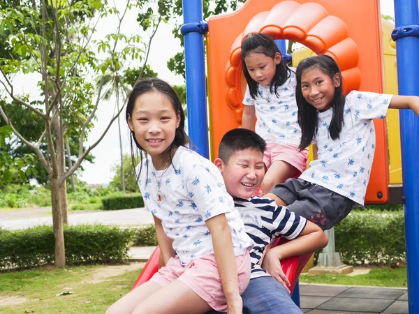 Feliz asiático niños sentado en playground juntos en el parque outd —  Fotos de Stock