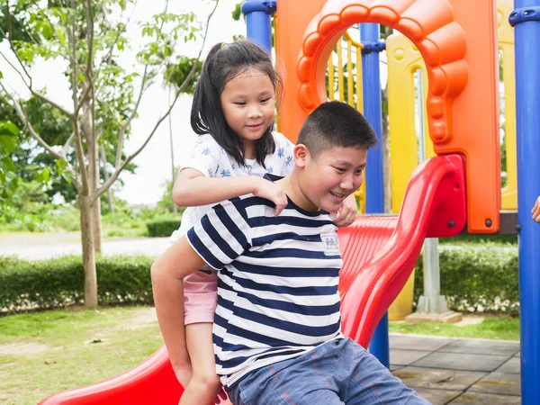 Feliz asiático niños sentado en playground juntos en el parque outd — Foto de Stock