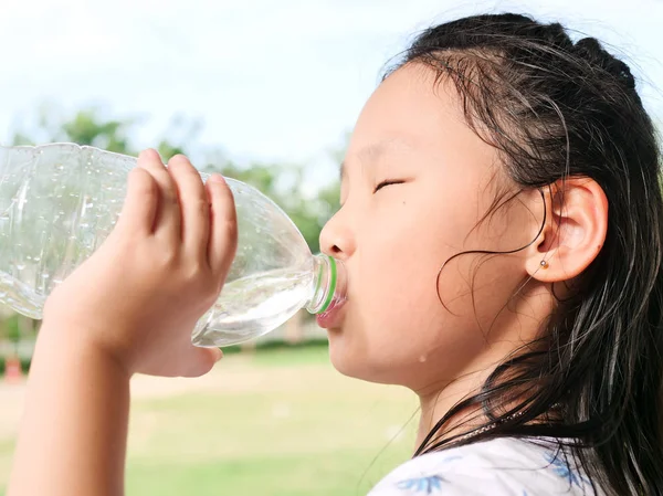 Aziatisch meisje drinken een fles water buiten. — Stockfoto