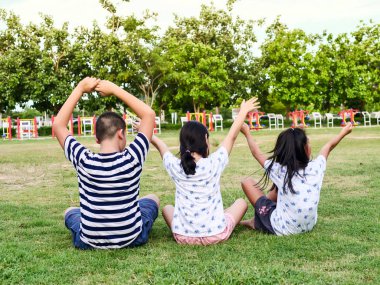 Parkta açık yeşil çimenler üzerinde oturan erkek ve kız arkası.