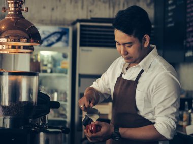 Mutlu Asya barista latte için kırmızı kahve fincanı içine süt dökme bir