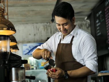 Mutlu Asya barista latte için kırmızı kahve fincanı içine süt dökme bir