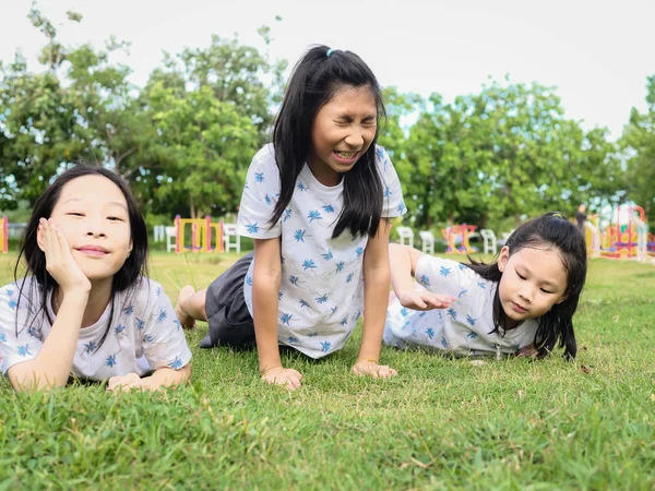 Χαρούμενα κορίτσια της Ασίας που θέτει κάτω σε πράσινο γρασίδι εξωτερική μαζί, l — Φωτογραφία Αρχείου