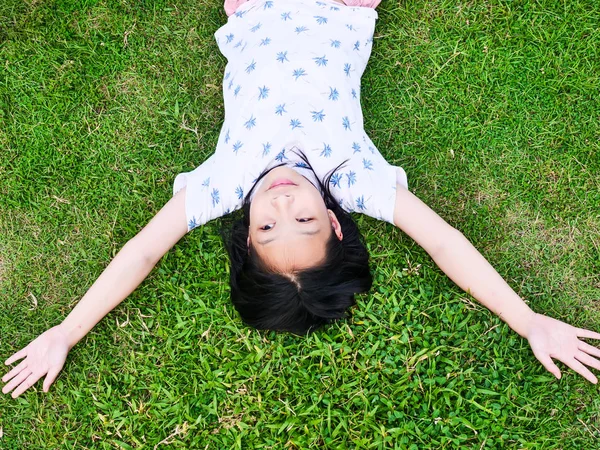 Ázsiai lány fekve a zöld fű kültéri életmód koncepció. — Stock Fotó