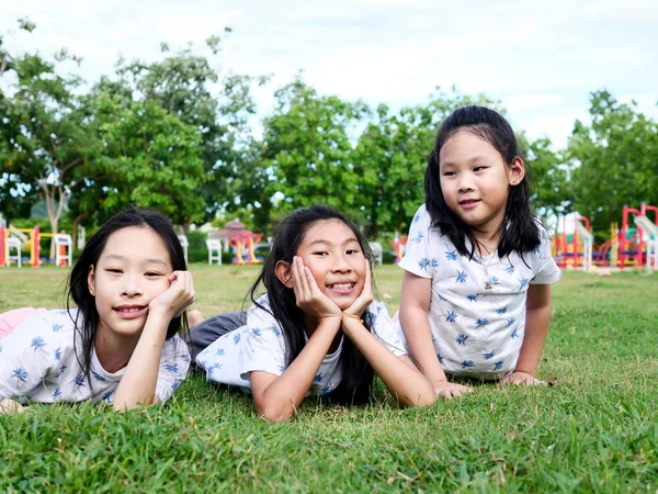 Szczęśliwy Asian dziewcząt ustanawiające w dół na zielony trawa na wolnym powietrzu razem, l — Zdjęcie stockowe