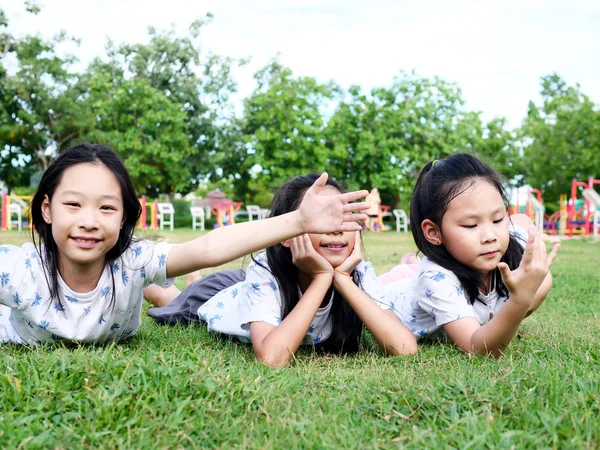 Glücklich asiatische Mädchen legen sich auf grünem Gras im Freien zusammen l — Stockfoto