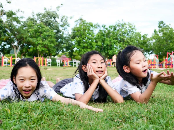 Szczęśliwy Asian dziewcząt ustanawiające w dół na zielony trawa na wolnym powietrzu razem, l — Zdjęcie stockowe