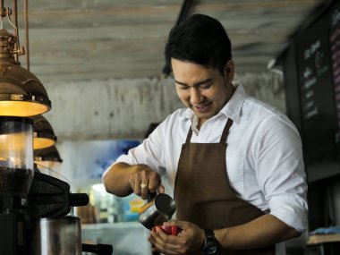 Mutlu Asya barista latte için kırmızı kahve fincanı içine süt dökme bir