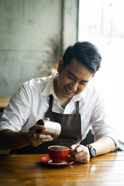 Asijské barista sype čokoládový prášek na pití v červeném poháru. — Stock fotografie