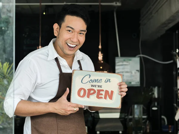 Cheerful Asian barista man holding welcome board in front of cof — Stock Photo, Image