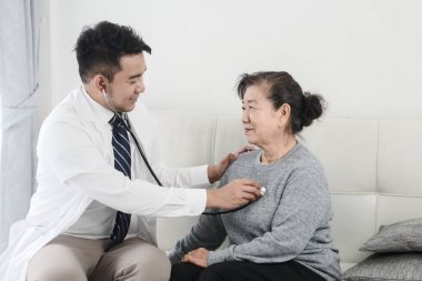 Asyalı doktor ofiste onun hasta yaşlı kadın kontrol.