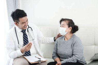 Asyalı doktor ofiste onun hasta yaşlı kadın kontrol.