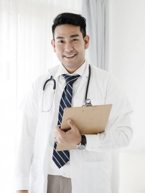 Pencerenin yanında duran mutlu kendine güvenen Asyalı doktor, yaşam tarzı con