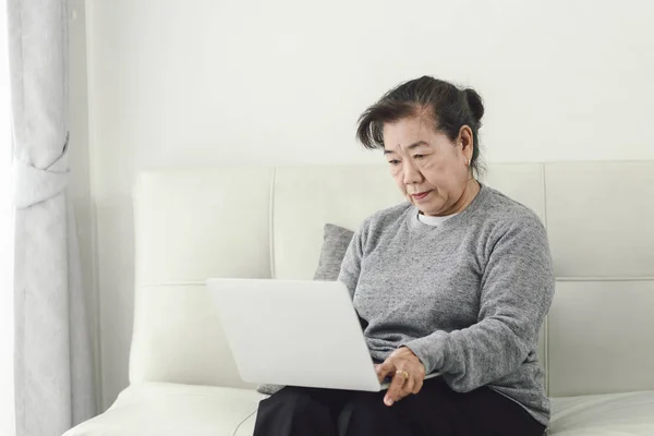 Asyalı yaşlı kadın evde dizüstü bilgisayar kullanarak, yaşam tarzı kavramı. — Stok fotoğraf