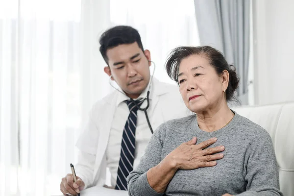 Asian lekarz sprawdzanie w górę jego pacjent stary Kobieta w biuro. — Zdjęcie stockowe