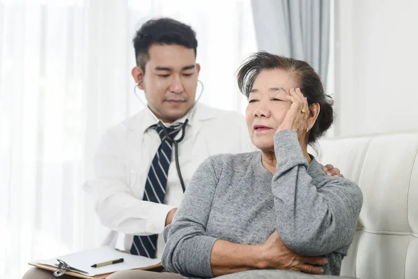 Aziatische arts controleren van zijn patiënt oude vrouw in Office. — Stockfoto