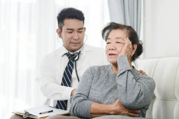 Asiatische Arzt Überprüfung bis seine geduldige alte Frau in Büro. — Stockfoto