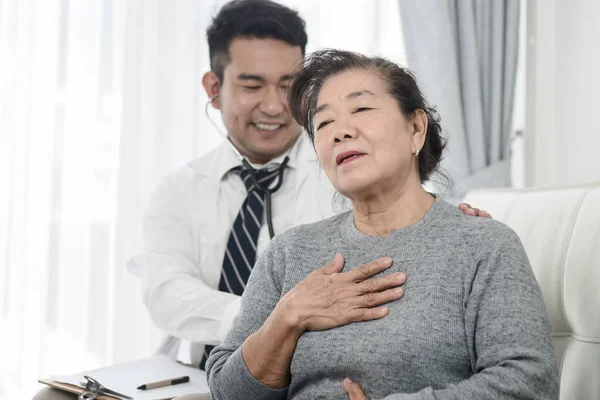 Aziatische arts controleren van zijn patiënt oude vrouw in Office. — Stockfoto