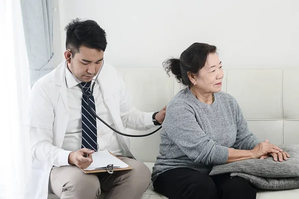 Asiatische Arzt Überprüfung bis seine geduldige alte Frau in Büro. — Stockfoto