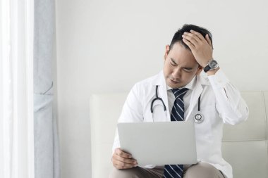 Asyalı doktor clini dizüstü bilgisayar ile çalışırken baş ağrısı hissi