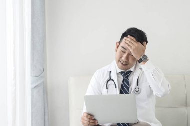Asyalı doktor clini dizüstü bilgisayar ile çalışırken baş ağrısı hissi