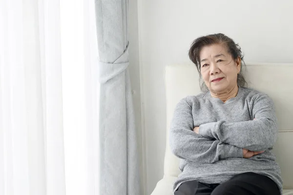 Feliz asiático senior mujer relajante en sofá en casa, estilo de vida con —  Fotos de Stock