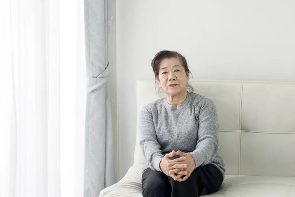 Счастливая азиатская пожилая женщина, отдыхающая на диване дома, стиль жизни con — стоковое фото