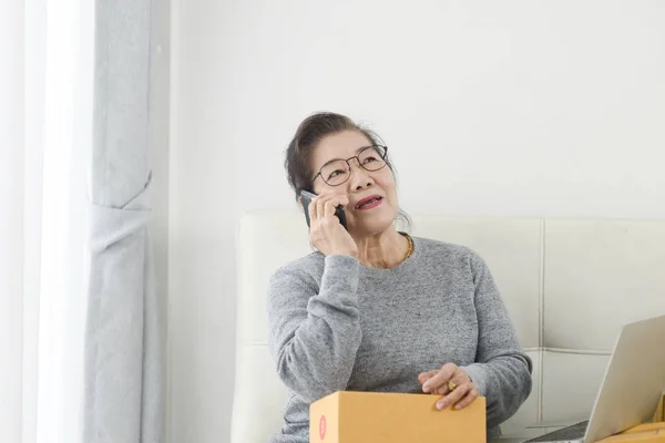 Asian senior woman taking order by phone, online business with p — стоковое фото