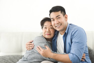 Asyalı anne oğluna sarılma ve evde kanepede oturan, lifest